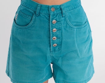 May include: Teal denim shorts with a button fly and five pockets. The shorts have a high waist and a relaxed fit.