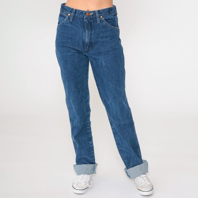 May include: A pair of blue denim jeans with a high waist and a straight leg fit. The jeans have a classic five-pocket design and are cuffed at the hem.