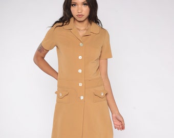May include: A brown short-sleeved collared dress with a button-up front and two patch pockets. The dress has a slightly A-line silhouette.