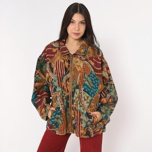 May include: A long-sleeve zip-up jacket featuring a multi-colored abstract pattern in shades of brown, teal, burgundy, and gold. The garment includes a fold-over collar, a full-length front zipper, and two side pockets, showcasing a complex print.