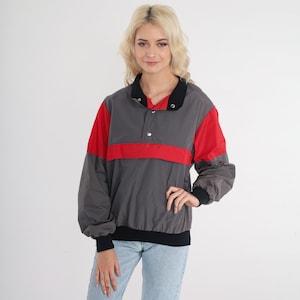 May include: A grey, red and black colour block windbreaker jacket with a snap button closure.