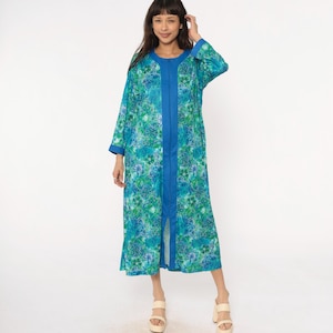 May include: A long, flowing robe in shades of teal and blue, adorned with a floral pattern. The robe features a contrasting blue trim along the front and sleeves. The garment is knee-length and has a relaxed fit.