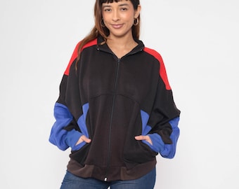 May include: A black zip-up jacket with red and blue color blocking. The jacket has two pockets and a ribbed hem.