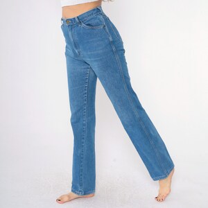 Op de afbeelding: Een lichtblauwe jeans met een rechte pijp en een hoge taille. De jeans heeft een klassiek ontwerp met vijf zakken en een knoopsluiting.