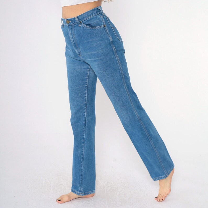 Op de afbeelding: Een lichtblauwe jeans met een rechte pijp en een hoge taille. De jeans heeft een klassiek ontwerp met vijf zakken en een knoopsluiting.