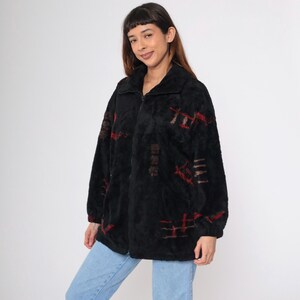 May include: Black fleece jacket with a zip fastening and a geometric pattern in red, brown and white.