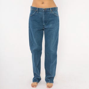 May include: Blue denim jeans with a classic straight-leg fit. The jeans have a button and zipper closure, with front and back pockets. The denim has a medium wash and a slightly faded appearance. The jeans are a timeless wardrobe staple.