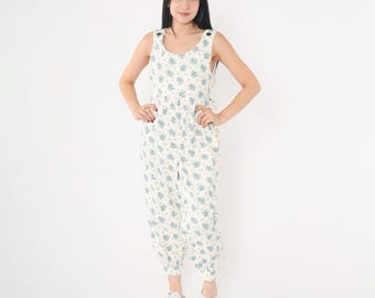 Op de afbeelding: Een witte jumpsuit met een blauw bloemenpatroon. De jumpsuit heeft een ronde hals en is mouwloos.