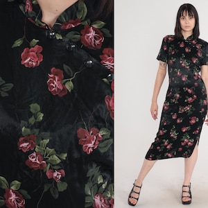 Könnte beinhalten: Schwarzes Midikleid mit Rosenmuster. Das Kleid hat kurze Ärmel, einen Stehkragen und einen Seitenschlitz. Die Rosen sind rot und die Blätter grün.