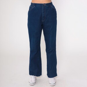 K&ouml;nnte beinhalten: Dunkelblaue Jeanshose mit hoher Taille und ausgestelltem Bein. Die Hose hat ein klassisches F&uuml;nf-Taschen-Design mit Knopf- und Rei&szlig;verschluss. Der Denim ist ein einfarbiger, mittelschwerer Stoff.