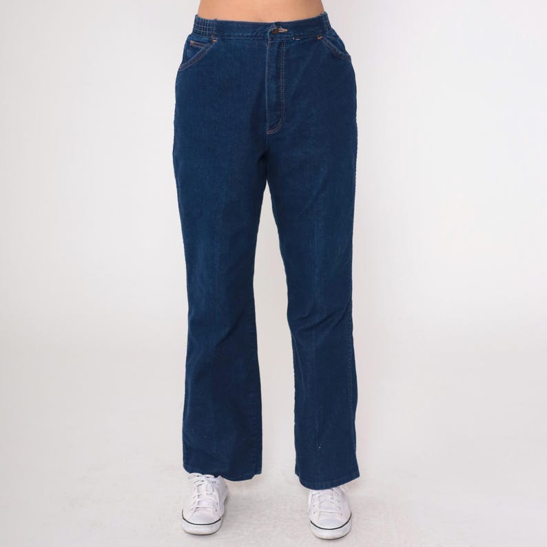 K&ouml;nnte beinhalten: Dunkelblaue Jeanshose mit hoher Taille und ausgestelltem Bein. Die Hose hat ein klassisches F&uuml;nf-Taschen-Design mit Knopf- und Rei&szlig;verschluss. Der Denim ist ein einfarbiger, mittelschwerer Stoff.