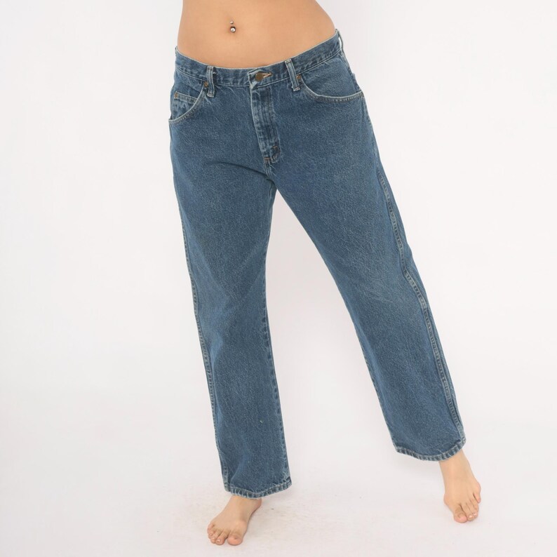 May include: Blue denim jeans with a classic five-pocket design. The jeans have a straight leg cut and a button and zipper closure. The denim is a medium wash, and the jeans appear to be unworn.