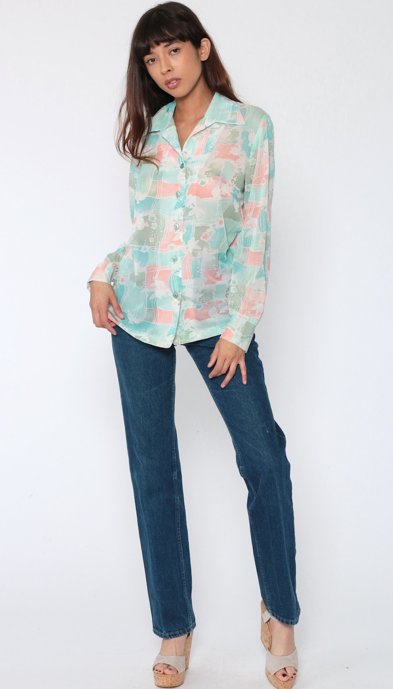 Puede incluir: Blusa transparente con botones y estampado en tonos pastel de color turquesa, melocot&oacute;n y blanco. La camisa de manga larga se combina con vaqueros azul oscuro. La persona lleva sandalias de plataforma.