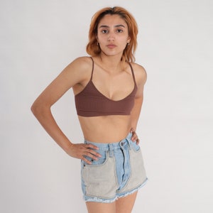 Puede incluir: Una mujer con un top de tirantes marr&oacute;n de canal&eacute; y pantalones cortos de mezclilla azul claro con dobladillo deshilachado.