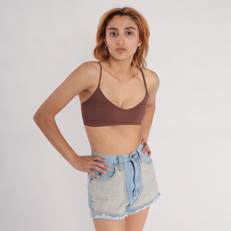 Puede incluir: Una mujer con un top de tirantes marr&oacute;n de canal&eacute; y pantalones cortos de mezclilla azul claro con dobladillo deshilachado.
