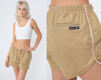 Può includere: Pantaloncini color cachi con bordatura bianca sui lati. Hanno un elastico in vita con coulisse e una tasca posteriore con zip. L'etichetta sulla tasca recita "PRIVATE CLUB".