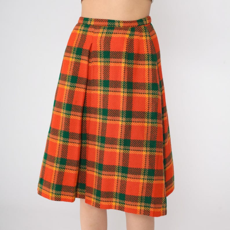 May include: A knee-length skirt with a plaid pattern in shades of orange, green, and yellow.