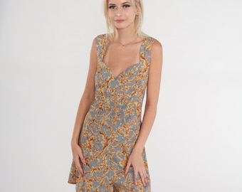 Könnte beinhalten: Ein ärmelloses Kleid mit einem herzförmigen Ausschnitt und einem gold-schwarzen Blumendruck. Das Kleid hat ein tailliertes Oberteil und einen ausgestellten Rock.