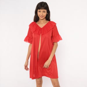May include: A bright red robe featuring a wide ruffled collar and short ruffled sleeves. The garment has an open front design that falls to a mid-thigh length, crafted from a smooth, lightweight fabric with a subtle sheen throughout the entire piece.
