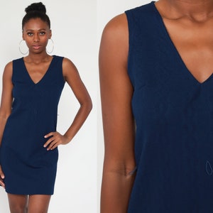 Può includere: Un abito blu navy senza maniche con scollo a V.