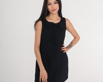 May include: A black sleeveless dress with a bow at the neckline and a row of buttons down the front.