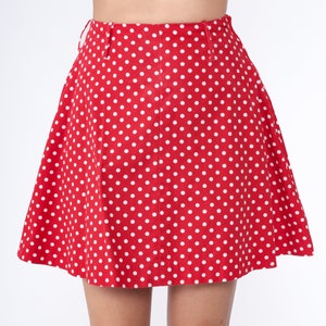 Peut inclure: Une jupe rouge &agrave; pois blancs. La jupe est trap&egrave;ze et a une taille haute.