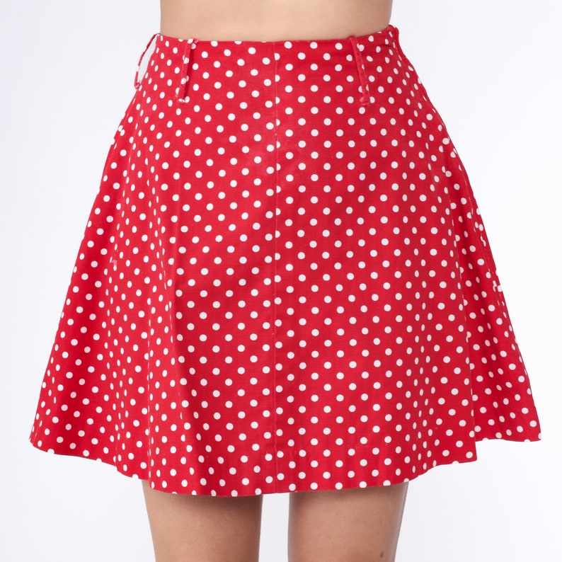 Peut inclure: Une jupe rouge &agrave; pois blancs. La jupe est trap&egrave;ze et a une taille haute.