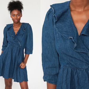 May include: A blue denim dress with a ruffled collar and a wrap-style bodice. The dress has a short, flared skirt and three-quarter sleeves.