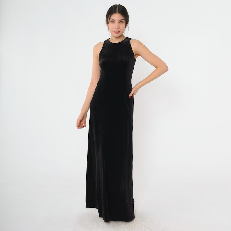 Może przedstawiać: Czarna, bezrękawowa sukienka maxi z weluru. Sukienka ma prosty, elegancki design i prosty kr&oacute;j.