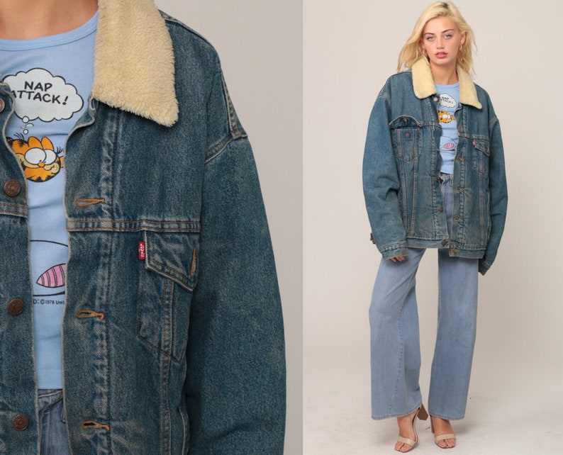 Puede incluir: Una chaqueta de mezclilla azul con cuello de sherpa color crema, cierre de botones met&aacute;licos y dos bolsillos en el pecho. Debajo, una camiseta azul claro con un gr&aacute;fico de un gato y el texto NAP ATTACK! junto a pantalones vaqueros anchos.