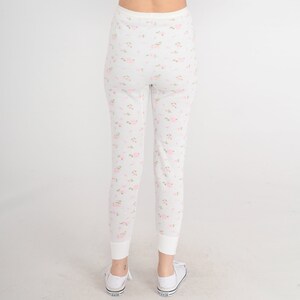 May include: White thermal underwear with a pink floral pattern. The underwear has a ribbed texture and a fitted silhouette.