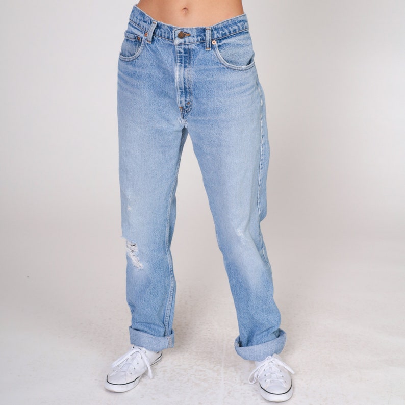 May include: Light blue denim jeans with a distressed look, featuring a cuffed hem and a relaxed fit.