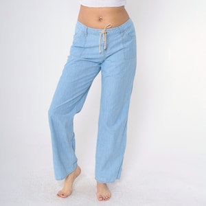 May include: Light blue denim pants with a drawstring waist and two large pockets on the front.