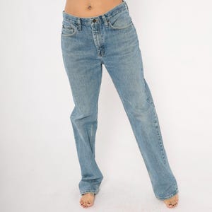 Peut inclure: Jean bleu clair avec une coupe droite classique &agrave; cinq poches. Le jean pr&eacute;sente un d&eacute;lavage d&eacute;color&eacute;, cr&eacute;ant un look vintage. Le jean est port&eacute; pieds nus.