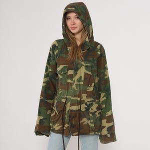 Jaqueta camuflada com capuz, estilo militar utilitário anos 90, com bolsos no peito, cintura com cordão, feita de algodão, com estampa grunge, gorpcore e streetwear. Tamanho G (L).