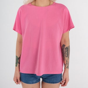 May include: A pink ribbed short-sleeved shirt with a round neckline.