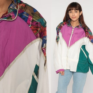 Puede incluir: Chaqueta cortavientos vintage con diseño de bloques de color. La chaqueta presenta una vibrante mezcla de colores, incluyendo blanco, magenta, verde azulado y una sección estampada en los hombros. Tiene cremallera completa y ribete dorado.