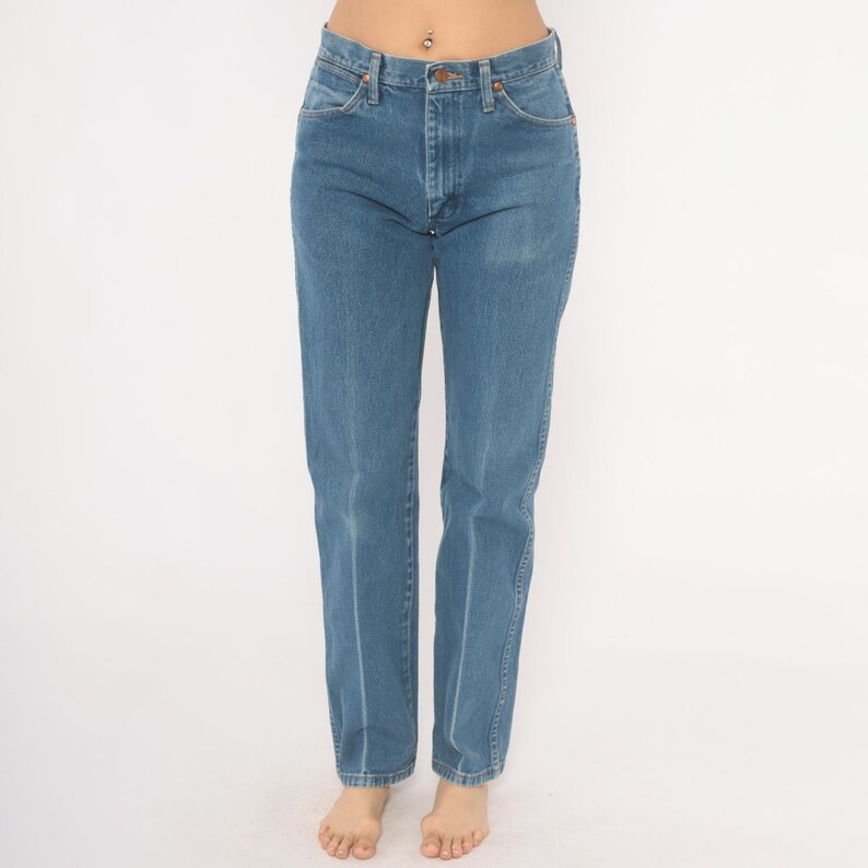 May include: Light blue denim jeans with a classic five-pocket design. The jeans have a straight leg cut and a medium wash. The jeans are made of a durable denim material and feature a button and zipper closure.