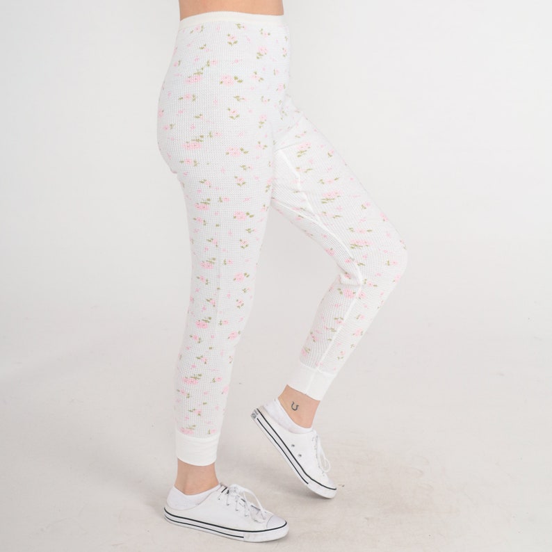 May include: White thermal leggings with a pink floral pattern. The leggings are made of a soft, stretchy fabric and have a comfortable fit.