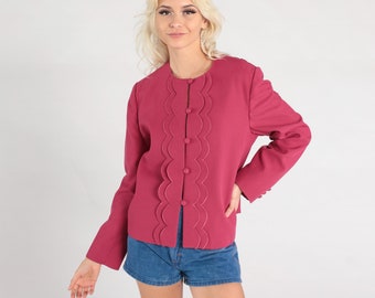 May include: A magenta-colored jacket with a scalloped design down the front, fastened with six buttons. The jacket has long sleeves and a round neckline. The model is wearing blue denim shorts.
