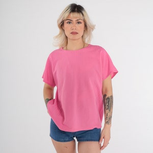 May include: A pink ribbed short-sleeved t-shirt with a round neckline.