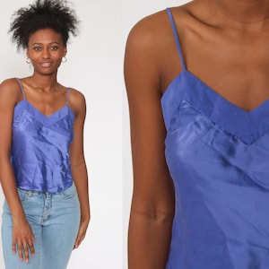 May include: A blue satin camisole top with thin straps. The top has a V-neckline and a relaxed fit.