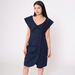 May include: A navy blue sleeveless dress with a large, wide collar and a double-breasted button closure.