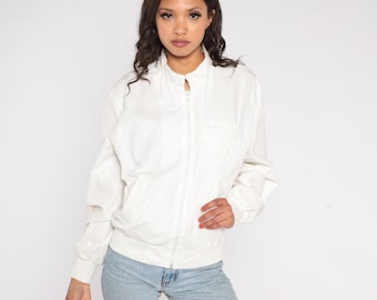 May include: A white zip-up jacket with a stand-up collar and a pocket on the left side.