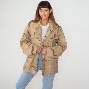 May include: A beige and brown camouflage jacket with a button closure and multiple pockets.
