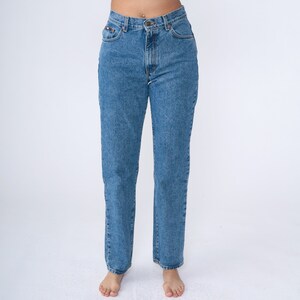 May include: Light blue denim jeans with a classic five-pocket design. The jeans have a straight leg cut and a button and zip closure. The jeans are made of a durable denim fabric and are suitable for everyday wear.
