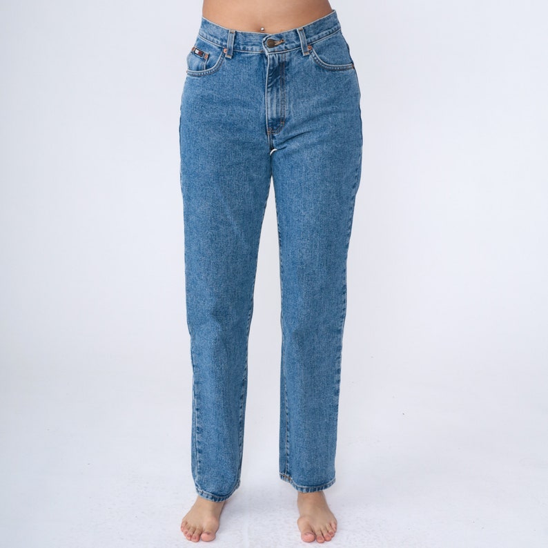 May include: Light blue denim jeans with a classic five-pocket design. The jeans have a straight leg cut and a button and zip closure. The jeans are made of a durable denim fabric and are suitable for everyday wear.