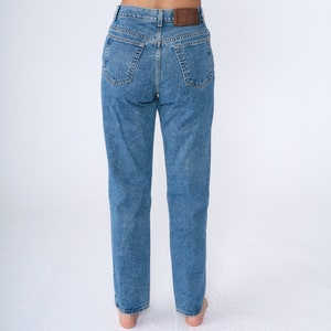 May include: Light blue denim jeans with a classic five-pocket design. The jeans have a straight leg cut and a brown leather patch on the back waistband. The jeans are made of a medium-wash denim.