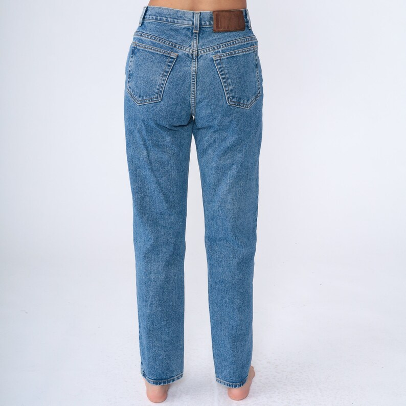 May include: Light blue denim jeans with a classic five-pocket design. The jeans have a straight leg cut and a brown leather patch on the back waistband. The jeans are made of a medium-wash denim.