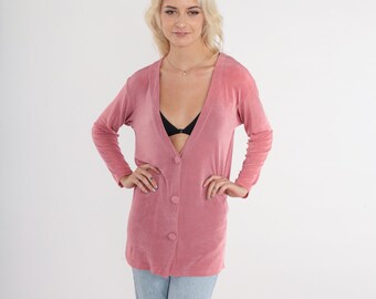 May include: A long-sleeved, dusty rose cardigan with a deep V-neck and button closure. The cardigan is made of a soft, stretchy fabric.